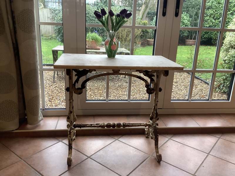 A small cast iron garden console table with marble top